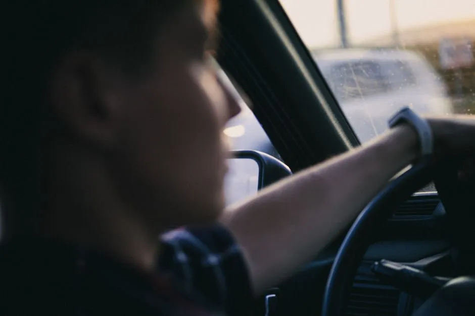 A person's hands on the steering wheel while driving, viewed from the driver's seat